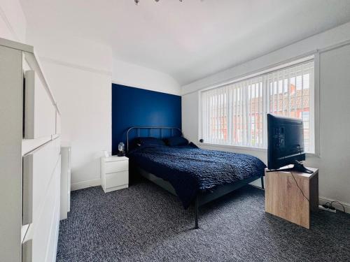 a bedroom with a bed and a blue wall at 2 Beds, Entire Home, Spacious Bedrooms, Garden in Aberdulais