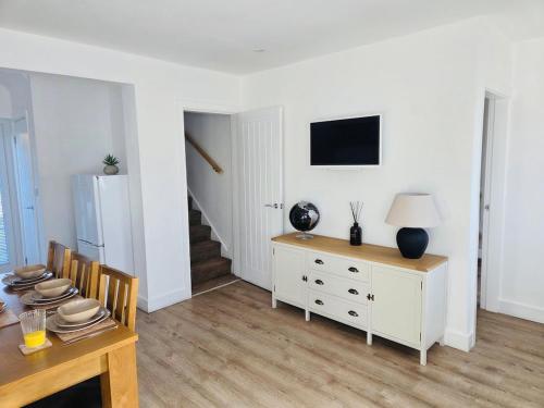 un salon avec une table et une télévision au mur dans l'établissement 3 Bedroom Village Stay - Comfort & Charm in Yorkshire, à Kippax