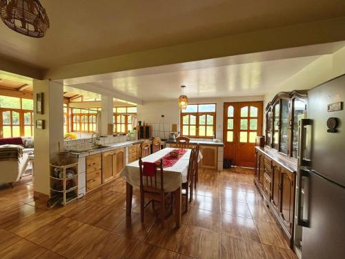 a large kitchen with a table and a refrigerator at Casa de campo con vista al Huascarán in Huaraz