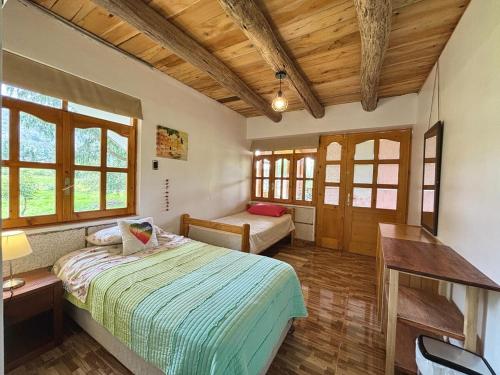 a bedroom with a bed and a desk and windows at Casa de campo con vista al Huascarán in Huaraz