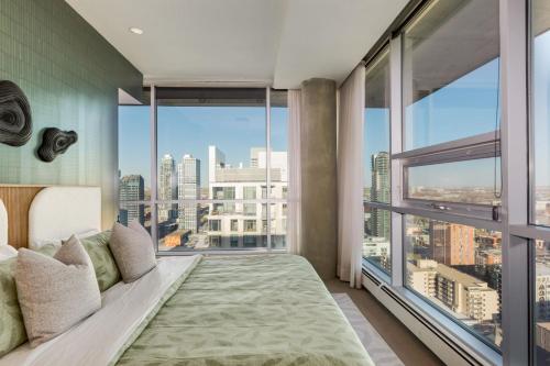 a bedroom with a bed and large windows at 2 Storey Penthouse Panoramic Views Parking Stampede in Calgary