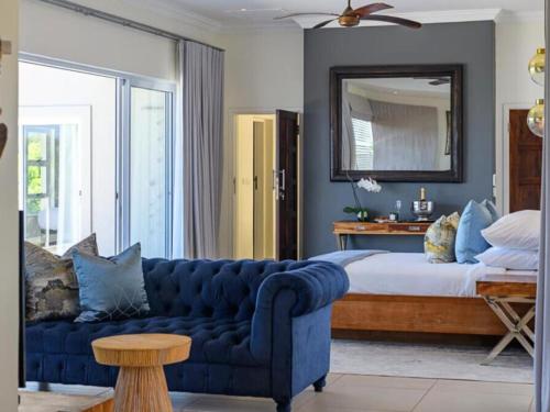 a bedroom with a blue couch in front of a bed at 11 On Fairway Villa by Euphoric Leisure in Southbroom