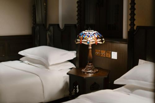 a lamp sitting on a table next to two beds at Beijing Xiaofengxian Former Residence Hotel Tiananmen Square Qianmen Store in Beijing