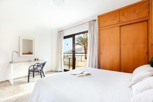 サンタ・エウラリア・デス・リウにあるアパルタメントス バイーアのベッドと机と窓のある寝室