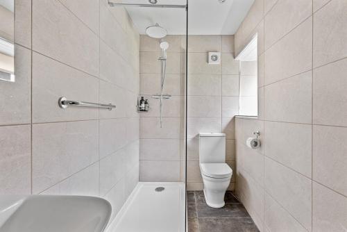 a white bathroom with a toilet and a shower at Fuchsia Cottage in Saint Endellion
