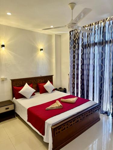 a bedroom with a large bed with red pillows at Pearl Breeze Apartments in Mount Lavinia
