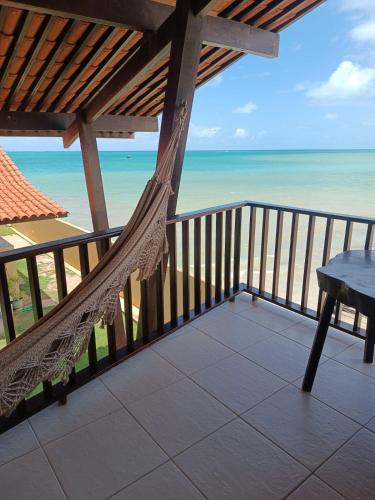 a hammock on a balcony overlooking the ocean at Pousada Dra Lindalva in Maragogi