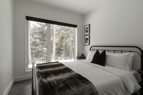 a bedroom with a bed and a large window at Scenic Bright - Sauna - Fire - 20 min Tremblant in La Conception
