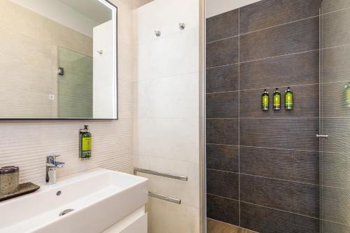 a bathroom with a shower and a white sink at LuxArt City Spa Gallery Residence Krk in Krk