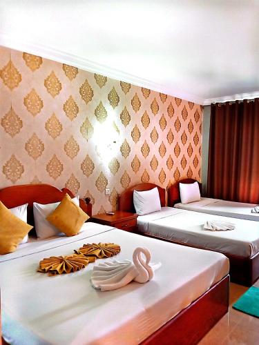two beds in a room with two swans on them at RatanakCity hotel in Banlung