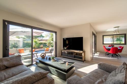 a living room with a couch and a tv at Villa Fabienne in city center with heated pool in Andernos-les-Bains