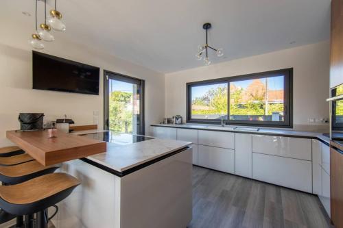 a kitchen with white cabinets and a large window at Villa Fabienne in city center with heated pool in Andernos-les-Bains