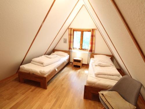 um quarto no sótão com 2 camas e uma cadeira em Twistesee Ferienhaus 36 em Wetterburg