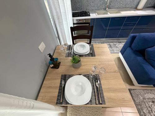 a dining table with two white plates and a blue couch at Riva'S Apartament in Shkodër