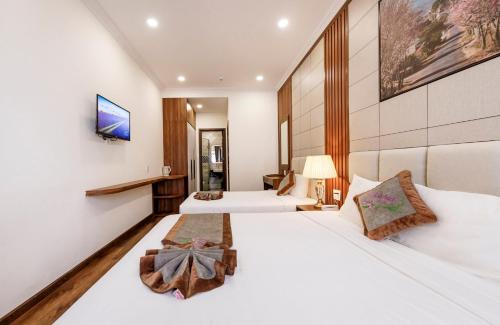una habitación de hotel con dos camas y un televisor en Wisteria Hotel Dalat, en Da Lat