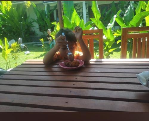 a girl sitting at a table with a plate of food at Najwahomestay in Lombok International Airport