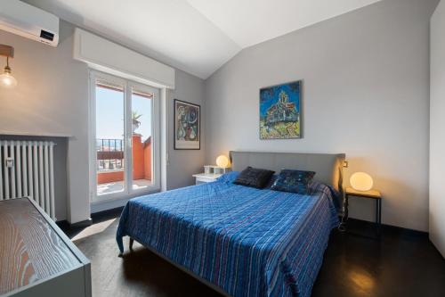 a bedroom with a bed with a blue comforter and a window at Attico Center with View and Terrace in Desenzano del Garda