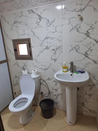 a white bathroom with a toilet and a sink at La Fibule D'or in Aït Benhaddou