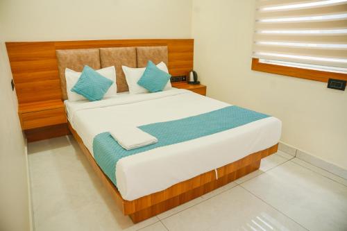 a bedroom with a large bed with blue pillows at Marine Grand Suite in Cochin