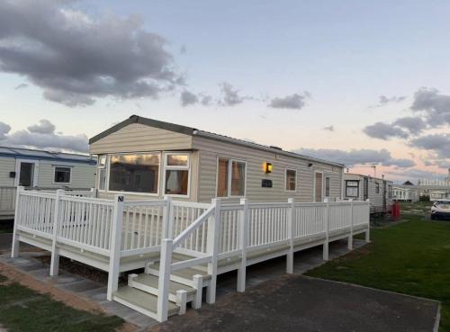 a mobile home with a white fence in a yard at Summer Breeze Deluxe Coastfields , ingoldmells in Skegness