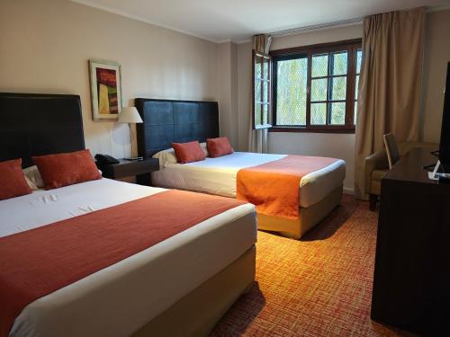 um quarto de hotel com duas camas e uma janela em Hotel Bahia Redonda em El Calafate