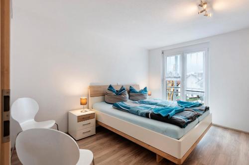 Un dormitorio con una cama con almohadas azules y una ventana. en Haus Haldenweg, en Höchenschwand