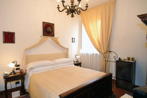 a bedroom with a bed with a chandelier and a window at Palazzo Tarlati - Hotel de Charme - Residenza d'Epoca in Civitella in Val di Chiana