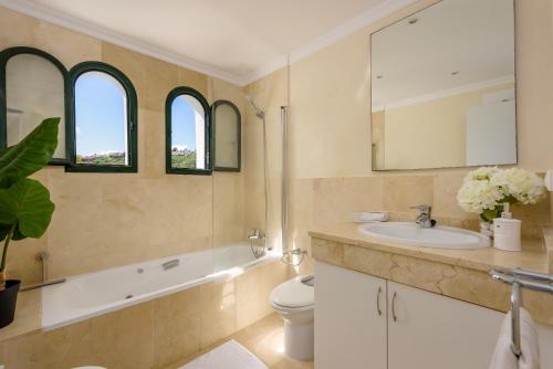 a bathroom with a sink and a toilet and two windows at Villa Bali in Manilva