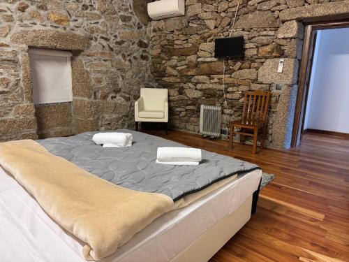 a large bed in a room with a stone wall at Miranda Guest House