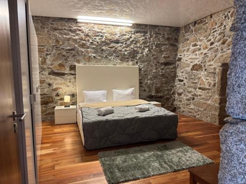 a bedroom with a bed and a stone wall at Miranda Guest House
