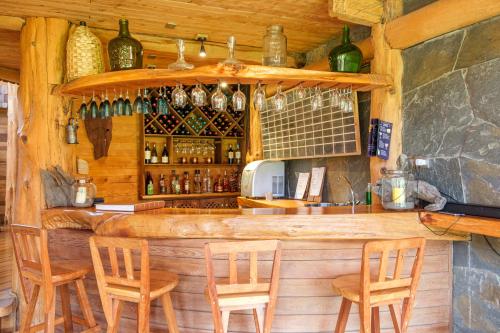 a bar with wooden chairs and bottles on the wall at Andes Lodge, Puelo Patagonia in Puelo