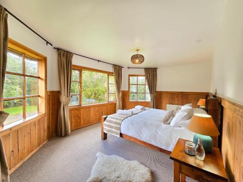 a bedroom with a large bed and windows at Andes Lodge, Puelo Patagonia in Puelo