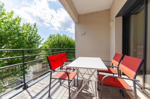 a balcony with a white table and four red chairs at Appartement Villa De L'Arche en plein centre-ville in Andernos-les-Bains