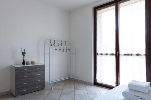 Un dormitorio con una cama, una cómoda y ventanas. en De Homes - Appartamento con Terrazza vicino Assago e Milano, en Buccinasco