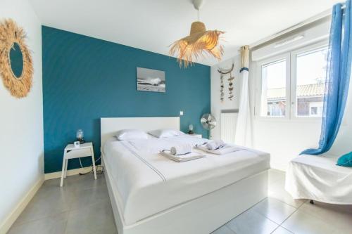 a bedroom with a white bed and a blue wall at Appartment Christine in Lège city for 5 persons in Lège-Cap-Ferret