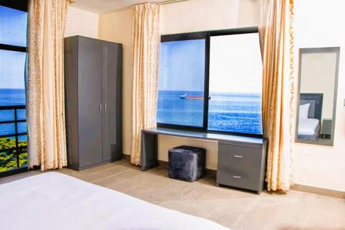 ein Schlafzimmer mit großem Fenster mit Blick auf das Meer in der Unterkunft Venue 360 in Freetown