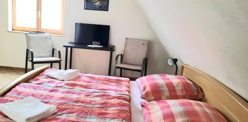 a room with a bed and two chairs and a tv at Gästehaus zum Schlossberg in Vogtsburg