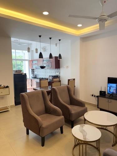 マウントラビニアにあるPearl Breeze Luxury Apartmentsの椅子とテーブルのある待合室、キッチン付