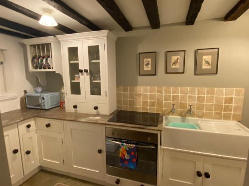 a kitchen with white cabinets and a sink at Crabapple Cottage adult only in Castle Donington