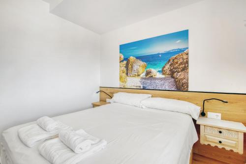 a bedroom with a white bed with a painting on the wall at Kuko Beach Denia in Denia