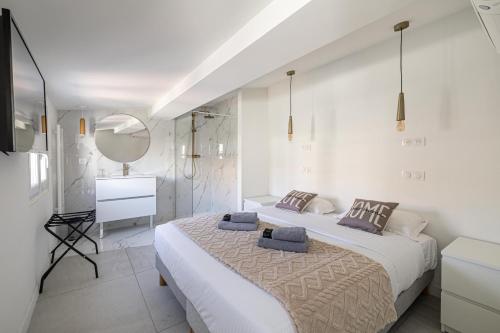 ein weißes Schlafzimmer mit einem Bett und einem Spiegel in der Unterkunft Cannes City Suites - 4 appartements neufs au coeur de Cannes in Cannes