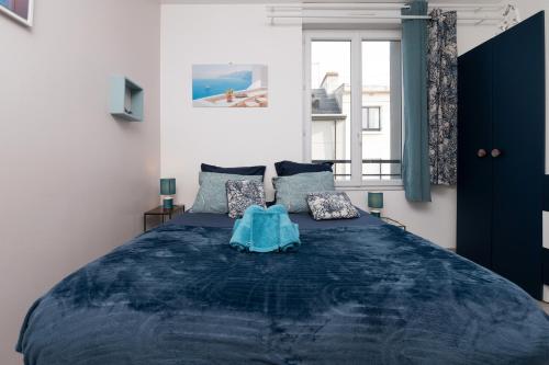 een slaapkamer met een groot blauw bed en een raam bij Santorin Îlot de Merville - Centre in Lorient