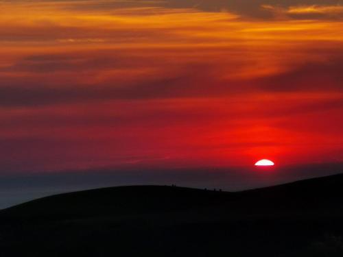 a sunset with the sun setting over a hill at Amazing Sunsets and Sea Views - Lodge Cabin Farm Stay - Caol Ila - Lodge 8 in Stranraer