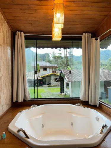 a bath tub in a room with a large window at Recanto Meu Pedacinho de Chão in Visconde De Maua