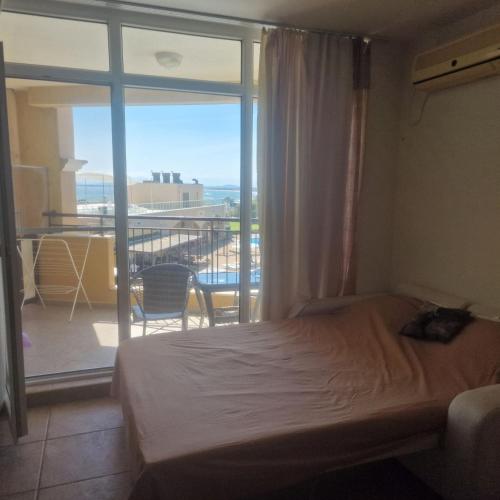 a bedroom with a bed and a view of a balcony at Charming Studio at the Seaside in Aheloy