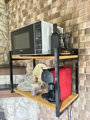 a microwave and a coffee maker on a shelf at Recanto Meu Pedacinho de Chão in Visconde De Maua