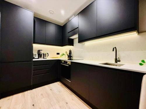 a kitchen with black cabinets and a sink at Old Compton Apartments in London