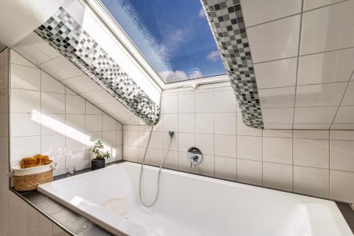 WinzelnにあるFerienwohnung Romanuの天窓付きのバスルーム(バスタブ付)