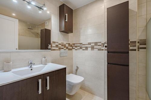 ein Badezimmer mit Waschbecken, Toilette und Spiegel in der Unterkunft Verodal 2 Bedroom Apartment in Los Cristianos