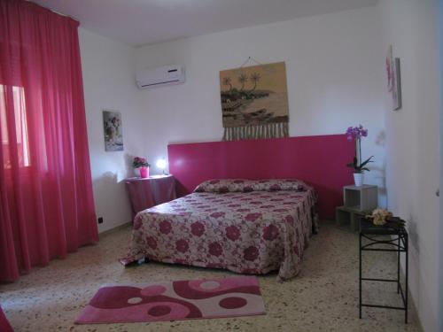 a bedroom with a pink bed and pink curtains at La Casa Dei Nonni in Custonaci